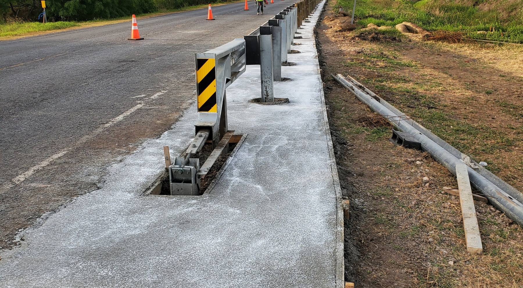 Fresh concrete shoulder beside a roadside guardrail