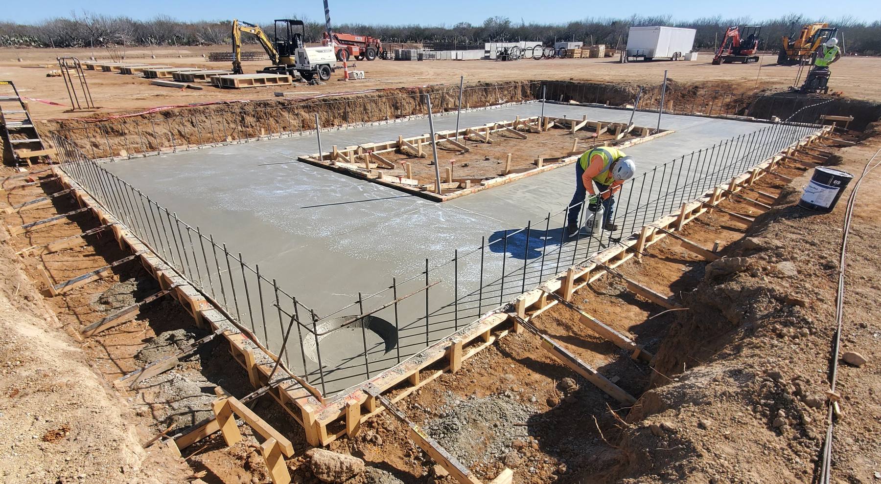 Concrete foundation slab with rebar and formwork being cured at an Ultra Pro job site